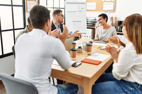 Gruppe von Menschen in einem Meeting, diskutiert und lacht an einem Bürotisch