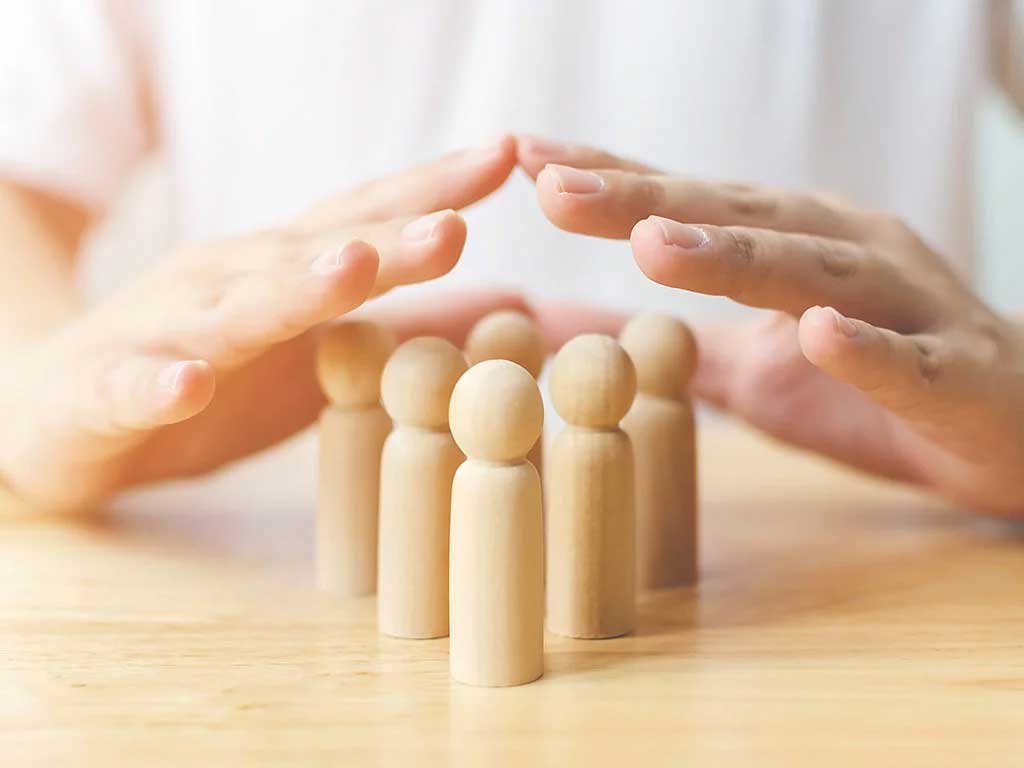 Hände schützen Holzfiguren – Symbol für Fürsorge, Sicherheit und Gemeinschaft.